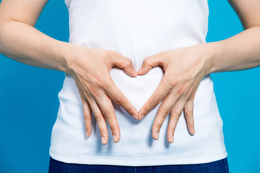 woman who makes a heart shape by hands on her stomach